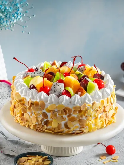 A classic fresh fruit cake with whipped cream and almond flakes, styled with a light and cheerful background to create a perfect e-commerce image for Bakingo.