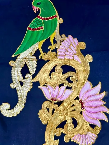 A finished piece of Tanjore art on fabric, featuring a vibrant parrot and lotus flowers. This demonstrates how traditional techniques can be adapted for different mediums.