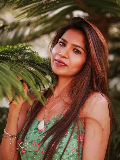A gentle and engaging pose, interacting with the natural elements. Her soft smile and the way she holds the branch create a serene and peaceful mood.