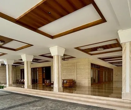 The portico and veranda of the Tirupur residence, showcasing the use of Italian marble on the exterior and a coffered ceiling with wood accents for a touch of warmth and sophistication.