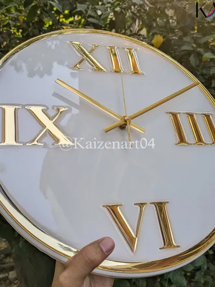 A classic and luxurious custom wall clock. This piece features large golden Roman numerals and a golden rim on a pristine white resin base, perfect for adding a touch of class to any room.