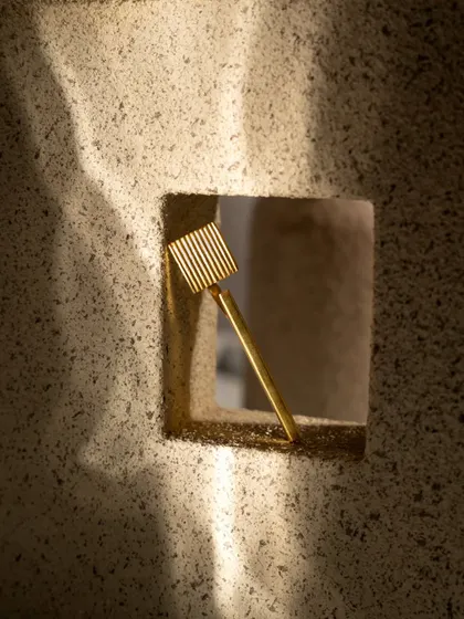 A creative product shot of a hair accessory, viewed through a hole in a textured block. This artistic framing draws the eye directly to the product and creates a memorable image.