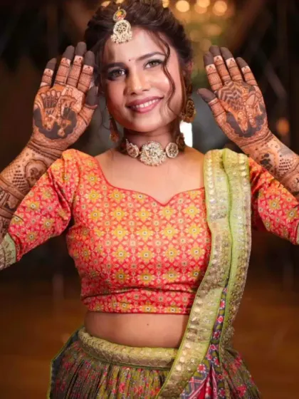 A happy bride showcasing her mehandi, which features portraits of the couple surrounded by traditional Rajasthani motifs.