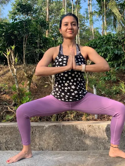 Goddess pose, Utkata Konasana, in a forest setting. This pose builds strength and confidence, and practicing it surrounded by the quiet stability of the trees feels incredibly empowering.