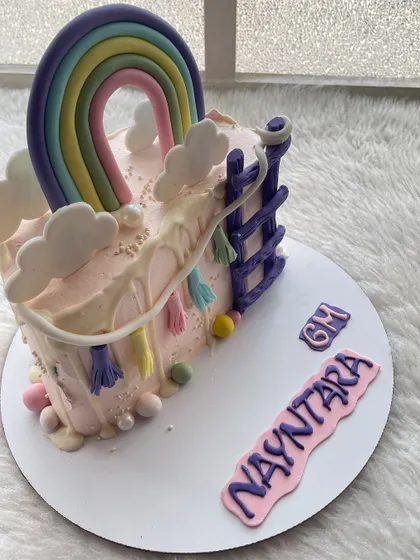 A colorful rainbow and slide-themed half-cake. This design is full of fun and playful details.