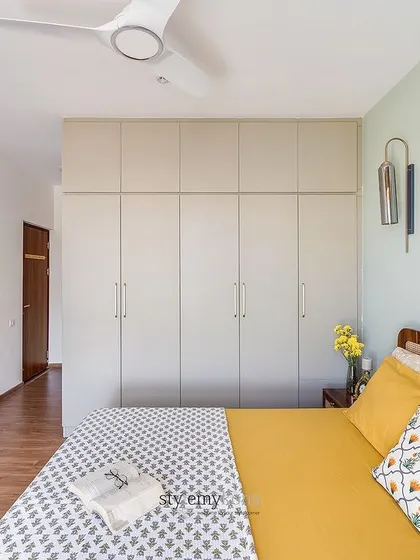 Another view of the guest bedroom, showing the simple, handle-less wardrobes and the cane headboard, which add texture and warmth to the neutral space.