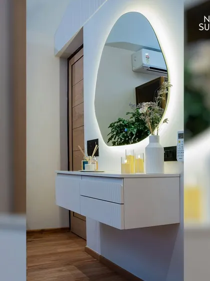 The dressing area in the eco-chic master bedroom. A floating white vanity with an organically shaped, backlit mirror creates a sleek and modern spot for getting ready, complementing the room's minimalist vibe.