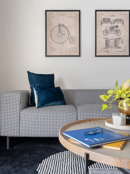 A quaint corner featuring a classic houndstooth patterned sofa and vintage patent art. This space was designed for a client who wanted an organized yet intimate environment, blending clean geometry with personal touches.