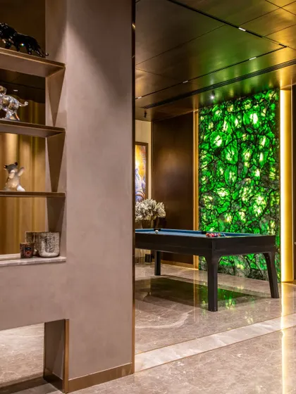 A striking feature in 'The Outhouse' is this glowing, backlit wall made from man-made green stone. It infuses the entertainment area with a vibrant, electric energy.