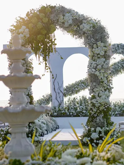 The floral arch and fountain together create a layered and picturesque scene. These elements work in harmony to build a romantic, garden-like atmosphere for the white wedding.