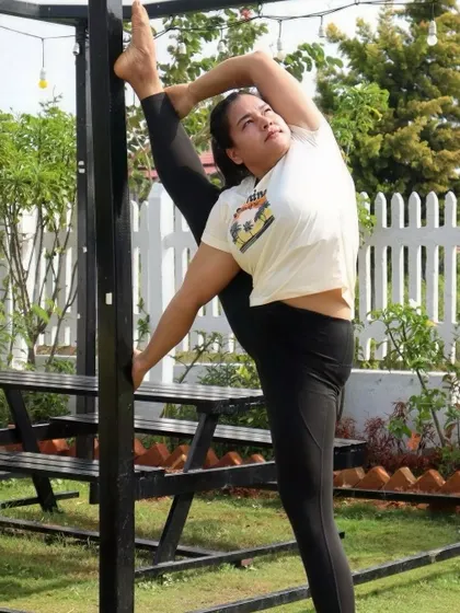 Using a post for support in a standing split, showcasing how we can use our environment to deepen our practice.