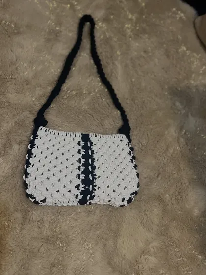 A casual shot of the black and white baguette bag on a soft rug, showing its simple and elegant shape.