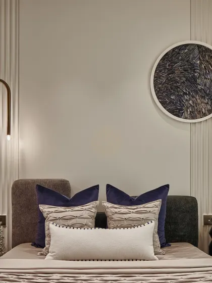 Another detail of the bedroom, focusing on the custom headboard and the circular art piece above it. The combination of different fabrics and textures adds depth and interest to the room.