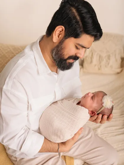 A father gazes lovingly at his newborn daughter. The connection between them is so clear and beautiful in this simple portrait.
