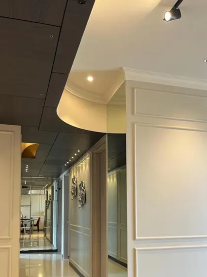 Luxury is in the details. Here, a gracefully curved ceiling detail meets classic wall paneling and mirrored surfaces, creating a sophisticated corridor that plays with light and reflection.