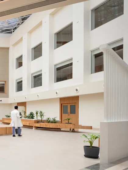 At Paras Yash Kothari Hospital, a central courtyard was created to improve daylight access and circulation. This space, featuring integrated wooden seating and planters, transforms the building's core into a healing environment.