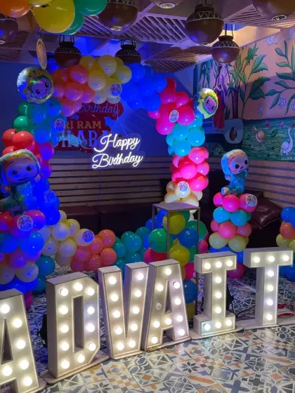 A vibrant Cocomelon theme with large light-up letters spelling out the birthday boy's name, Advait. The bright primary colors and character balloons make this a super fun setup for a 2nd birthday.