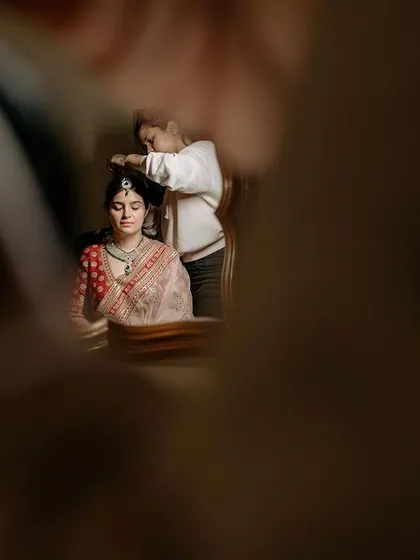 A creative, out-of-focus shot of the bride getting her hair done, capturing the mood of the getting-ready process.