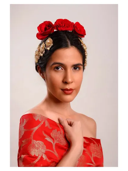 A conceptual ethnic portrait inspired by Frida Kahlo. The red floral headband and off-shoulder drape create a powerful and artistic image that blends tradition with a fine art aesthetic.