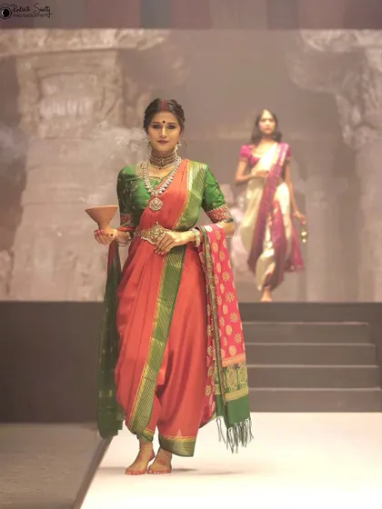 A powerful shot from the NAVATAAR show, where the model holds a traditional vessel. The composition, with another model in the background, creates a sense of depth and narrative on the stage.