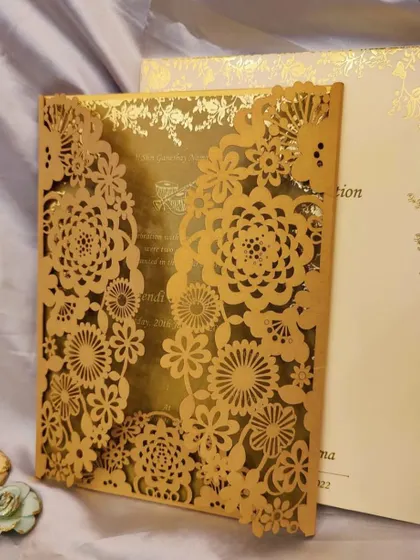 A masterpiece of laser cutting. This card features an incredibly detailed floral pattern cut into a gold metallic paper, creating a luxurious and unforgettable invitation.