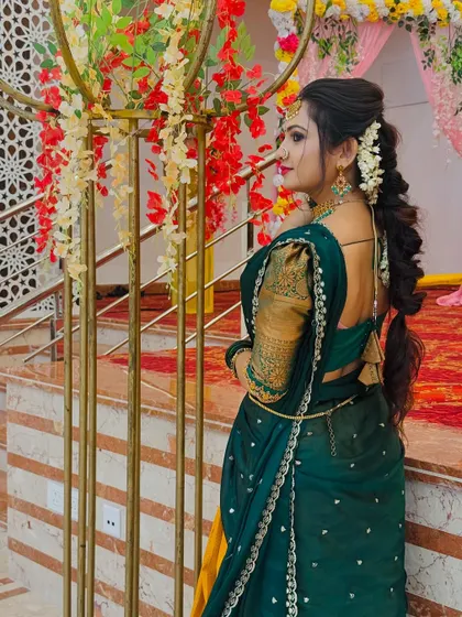 The back view showcases the beautiful braided hairstyle and the elegant fall of the half saree, perfect for capturing memorable photos at any event.