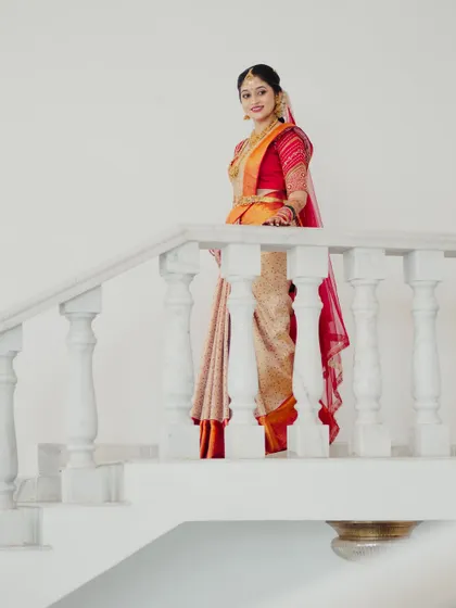 An elegant portrait of the bride on a staircase. The lighting highlights her radiant skin and the beautiful details of her makeup and Kanjeevaram half-saree.