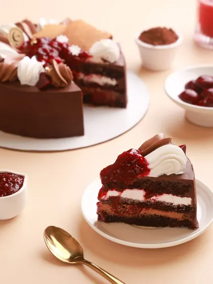 A perfect slice of our Black Forest Cake, showing the layers of rich chocolate, fresh cherry compote, and light vanilla cream.
