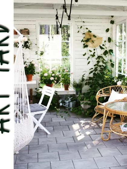 An inspiration shot of a bright, airy sunroom or covered patio filled with plants, a hammock chair, and wicker furniture, embodying the goal of creating a greener, more peaceful living environment.