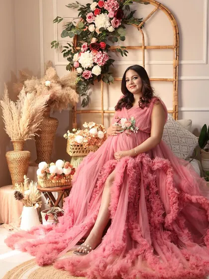 A beautiful solo portrait in a pink ruffled gown, seated gracefully in the boho setup. The soft colors and textures create a dreamy feel.