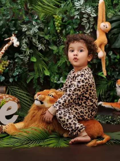 King of the jungle! A one-year-old boy confidently sits on a plush lion prop in his safari-themed session.