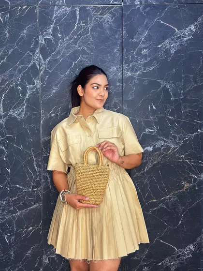 A beige pleated shirt dress paired with a mini straw bag. This is a perfect neutral, monochrome look for a summer day.