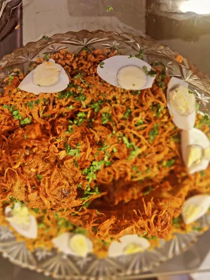 A beautifully presented platter of our special biryani, garnished with fried onions, fresh herbs, and boiled eggs. This is a staple for celebratory meals.
