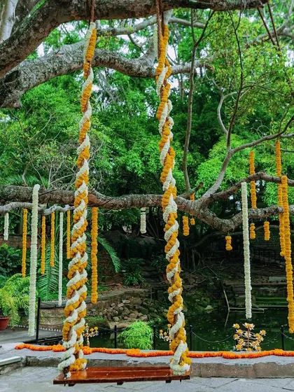 A beautiful floral swing at the Tamarind Tree venue, perfect for photos and quiet moments amidst the Haldi fun. The tree branches are adorned with hanging flower strings.