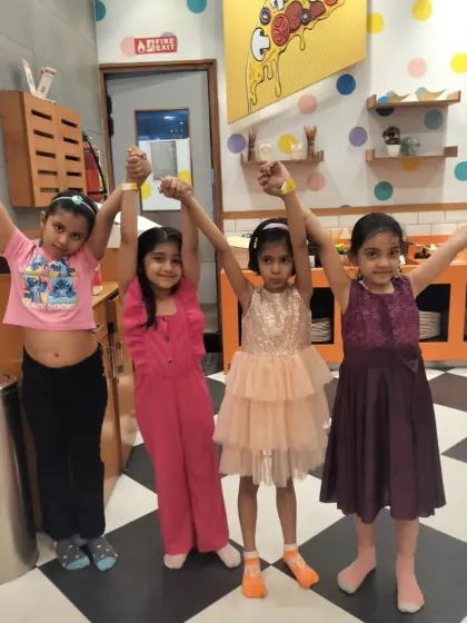 A group of friends raises their hands in celebration. The checkered floor and colorful decor of our cafe area provide a fun backdrop for party photos.