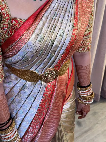 A stunning bridal look with a perfectly draped silk saree and traditional jewellery. The vaddanam accentuates the waist and holds the pleats in place.