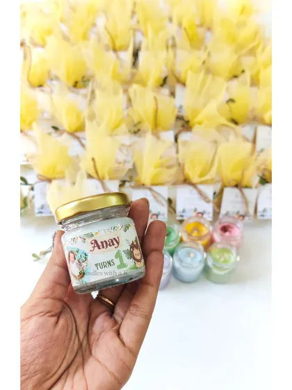 Holding one of the personalized jungle-themed candles, showing the custom sticker for Anay's first birthday.