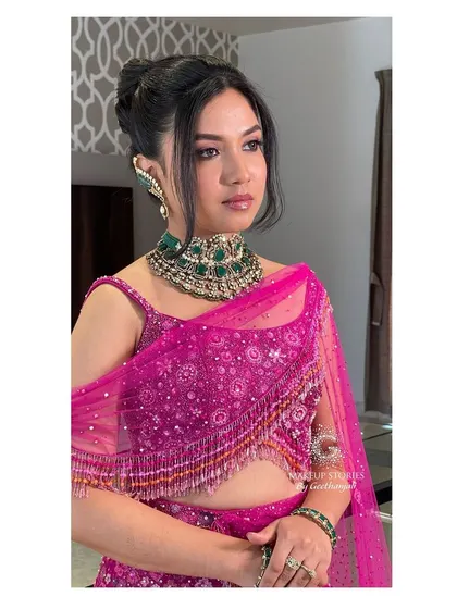 Drutha looking chic and modern for her reception. The makeup features a clean, winged liner and a glossy nude lip, paired with a stylish updo and a statement emerald choker.