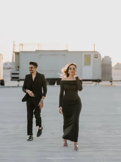 A dynamic shot of the couple walking towards the camera in the desert, their confident strides and stylish outfits creating a powerful, cinematic image.