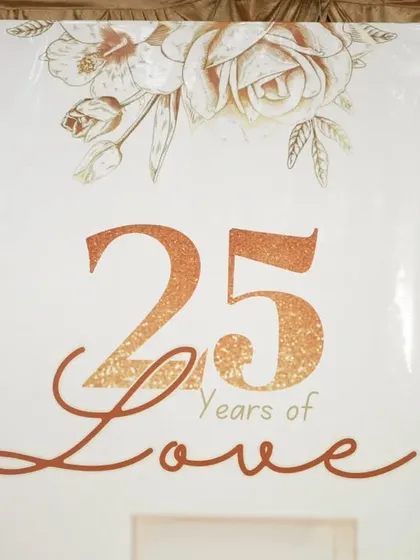 A close-up of the '25 Years of Love' sign against a shimmering gold sequin backdrop.