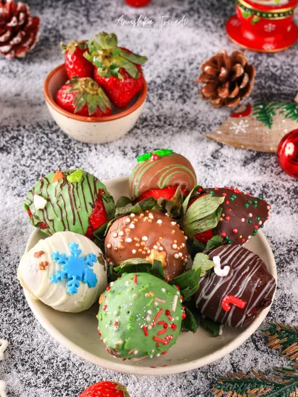 Christmas-themed chocolate-dipped strawberries, decorated with snowflakes and festive green drizzles on a snowy surface.
