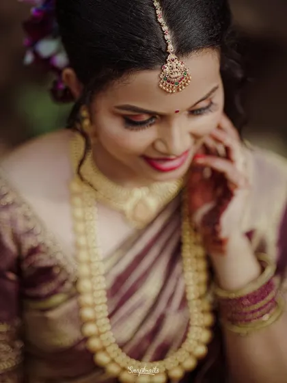 A close-up portrait of the bride, her head tilted slightly, highlighting her beautiful makeup, jewelry, and joyful expression.