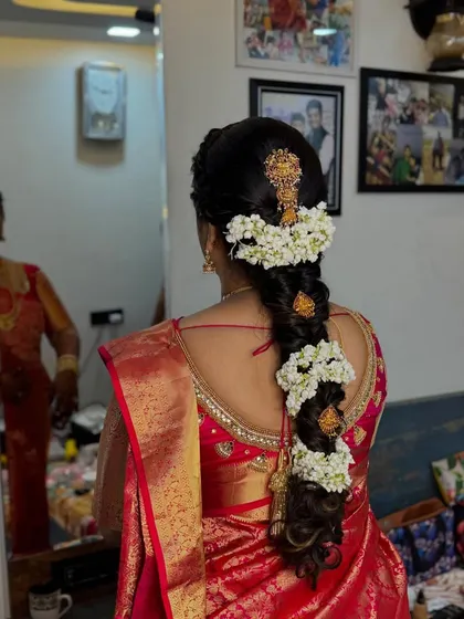 A detailed view of a traditional South Indian bridal braid, beautifully decorated with fresh jasmine flowers and gold accessories.