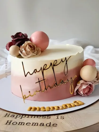 An elegant ombre cake in dusty rose tones, decorated with paper flowers and a gold "Happy Birthday" script for a mother's celebration.