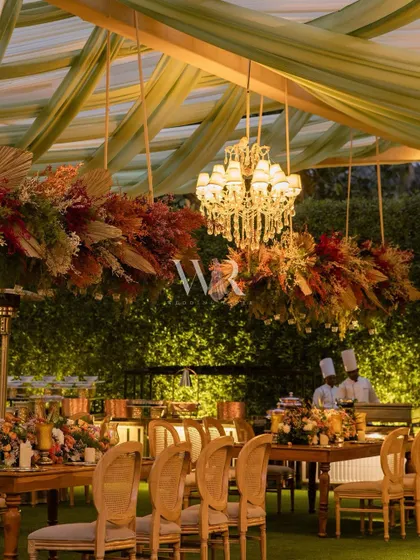 An intimate boho dining setup. We used a hanging installation of dried, earthy-toned florals over rustic wooden tables and cane-back chairs, creating a warm and textural experience for guests.