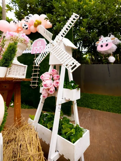Every detail is thoughtfully designed, like this decorative white windmill that adds an authentic touch to the farm theme. It's paired with fresh flowers and greenery to enhance the rustic, charming atmosphere of the party.