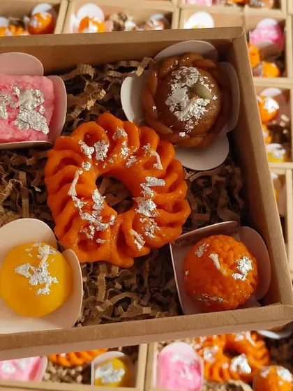 A close-up of a small gift box containing an assortment of Indian sweet-shaped candles. This is a great option for a small, thoughtful, and unique Diwali gift for colleagues or clients.