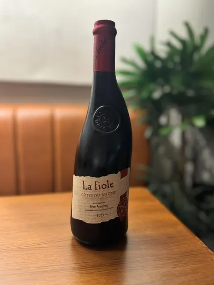 A bottle of La Fiole, a classic Côtes du Rhône from France, resting on our table. This is one of the many excellent bottles available for you to explore as part of our extended weekend hours.