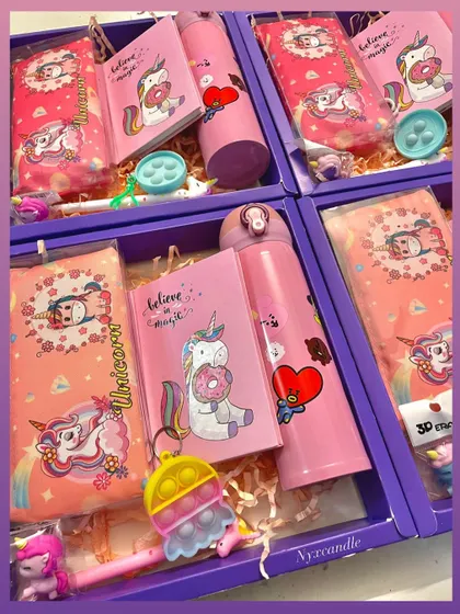 An overhead view of our Unicorn-themed hampers, showcasing the variety of items inside, including a pop-it keychain and cute stationery.