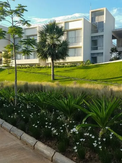 The residential blocks of the DRL Leadership Academy set against rolling green mounds. The campus is designed as a low-rise development where the built form is secondary to the landscape.